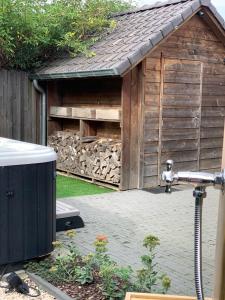 a small wooden shed with a pile of wood at Maas Lodge in Maaseik