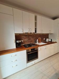 eine Küche mit weißen Schränken und einer Ziegelwand in der Unterkunft CENTRAL Apartament Urbana in Arad
