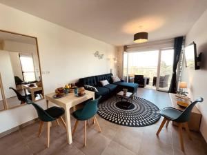 ein Wohnzimmer mit einem Sofa, einem Tisch und Stühlen in der Unterkunft RAVISSANT T2 AVEC VUE MAGIQUE SUR L'ETANG DE THAU in Balaruc-les-Bains