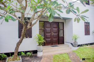 a house with a wooden door and a tree at Blooming polhena in Matara