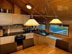 a kitchen with wooden cabinets and a table and two lights at Modern sports cabin on Sjusjøen with sauna and waxing room in Ringsaker