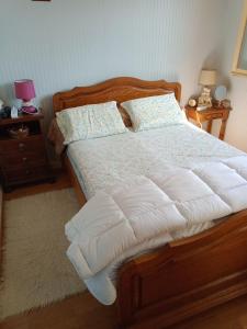 - une chambre dotée d'un lit en bois avec des draps et des oreillers blancs dans l'établissement Maison entière Garage et parking, à Montluçon