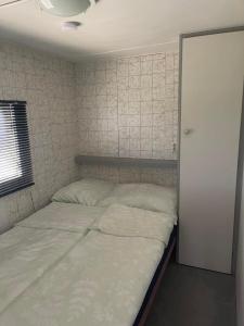 ein Schlafzimmer mit einem Bett mit weißer Bettwäsche und einer Tür in der Unterkunft Pronájem dřevěného mobilheimu Štít in Chlumec nad Cidlinou