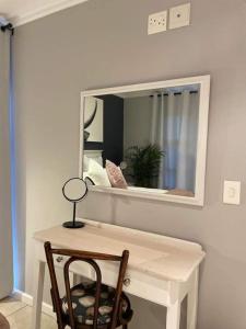 a mirror on a wall with a table and a chair at Lux apartment Plett in Plettenberg Bay