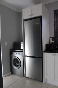 a kitchen with a refrigerator and a washing machine at Lux apartment Plett in Plettenberg Bay