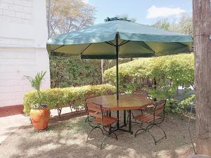een tafel en stoelen onder een groene parasol bij Arabella Suites - Karen in Karen