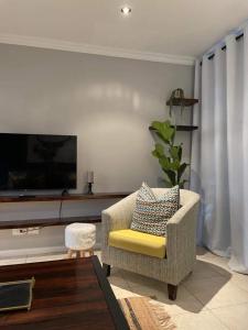 a living room with a chair and a tv at Lux apartment Plett in Plettenberg Bay