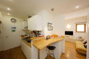 a kitchen with white cabinets and a wooden counter top at Siena UpTown - Sabrina's Cozy Apartment in Siena