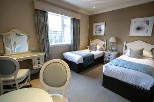 a hotel room with two beds and a table and chairs at International Hotel Killarney in Killarney