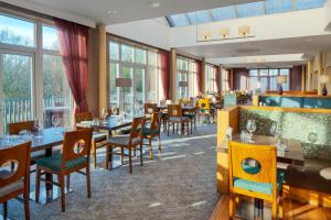 ein Restaurant mit Tischen, Stühlen und Fenstern in der Unterkunft The Telford Hotel, Spa & Golf Resort in Telford