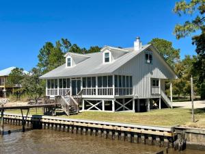 a large white house on a dock next to the water at Write on the Bay, a Waterfront Retreat in Coastal Alabama in Fairhope