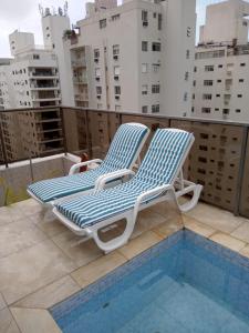 deux chaises longues assises à côté d'une piscine dans l'établissement Cobertura Duplex, à Guarujá