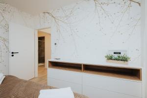 a bedroom with a white wall with branches on it at Apartmán BALIN X31 in Dolný Kubín
