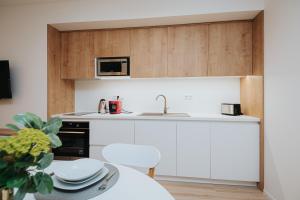 a kitchen with white cabinets and a table and a microwave at Apartmán BALIN X31 in Dolný Kubín