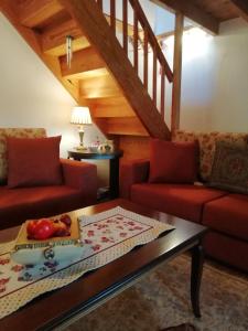 a living room with two red couches and a table at Cosy lake house, μια ανάσα πριν τη λίμνη in Kalyvia