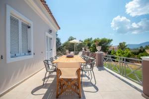 een patio met een tafel en stoelen op een balkon bij Elegant Villa Zakynthos in Kalamaki