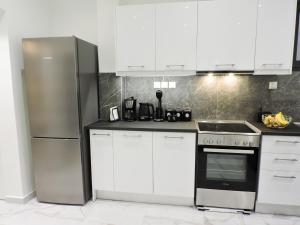 a kitchen with white cabinets and a stainless steel refrigerator at Apparlia Athens Luxury Apartment near Acropolis in Athens