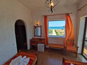a bedroom with a bed and a window with a view of the ocean at Hotel Tsagarakis Beach in Amoudara Herakliou
