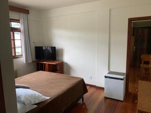 聖若阿金的住宿－Altos da Serra Hotel，一间小卧室,配有一张床和电视