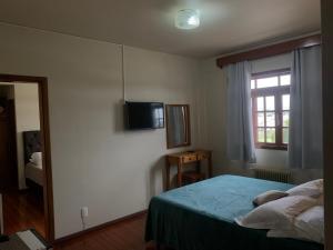 um quarto com uma cama e uma televisão na parede em Altos da Serra Hotel em São Joaquim