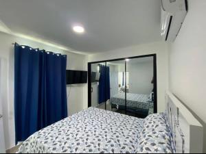 a bedroom with a bed with blue curtains and a mirror at Beautiful Cozy Los Jardines Santiago, 2 Floor in Santiago de los Caballeros