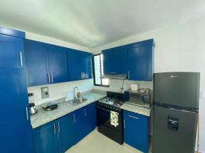 a kitchen with blue cabinets and a black refrigerator at Beautiful Cozy Los Jardines Santiago, 2 Floor in Santiago de los Caballeros