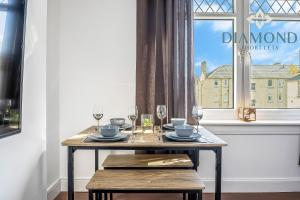 une table à manger avec des verres et une fenêtre dans l'établissement Cosy 2 Bed Apt West End Edinburgh FREE PARKING, à Édimbourg
