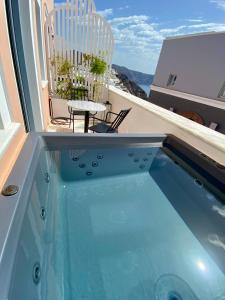 a plunge pool on a balcony with a table and chairs at ArmonOia Suites in Oia