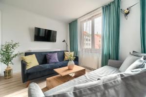 un soggiorno con divano blu e finestra di Apartament Milion Rynek Sienny Stare miasto Apartamenty No.1 a Stettino