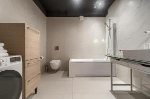 een badkamer met een bad, een wastafel en een wasmachine bij Apartament Milion Rynek Sienny Stare miasto Apartamenty No.1 in Szczecin