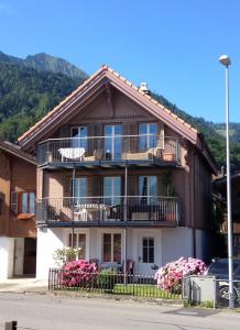 une grande maison avec un balcon et des fleurs devant. dans l'établissement Haus am See, à Därligen