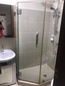 a shower with a glass door next to a sink at Condotel Type in Manila