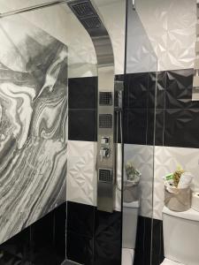 baño con ducha y pared de azulejos blancos y negros. en Apartman Stefan Lux en Vrdnik