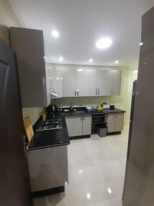 a large kitchen with white cabinets and black counter tops at Residence vip in Nador