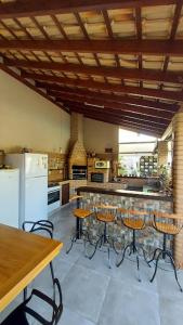 a kitchen with a bar with stools and a refrigerator at Chácara Renil in Olímpia