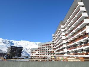 un gran edificio de apartamentos con montañas en el fondo en Studio Les Menuires, 1 pièce, 2 personnes - FR-1-452-51, en Les Menuires