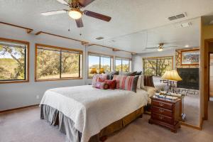 a bedroom with a bed with a ceiling fan and windows at Spicewood Treehouse in Spicewood