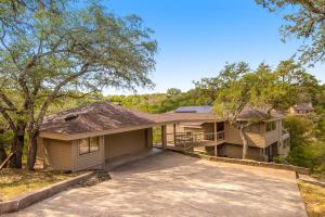 a house with a driveway and trees at Spicewood Treehouse in Spicewood