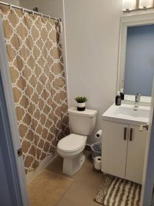 La salle de bains est pourvue de toilettes, d'un lavabo et d'un rideau de douche. dans l'établissement Midtown 4 bedroom home Free Wi-Fi and parking, à Toronto