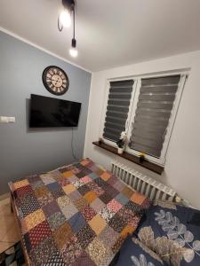 a bedroom with a bed and a clock on the wall at Apartament Leon in Wałbrzych