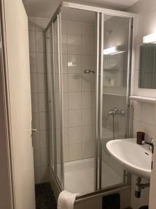 ein Bad mit einer Dusche und einem Waschbecken in der Unterkunft Honolulu Hotel in Bregenz