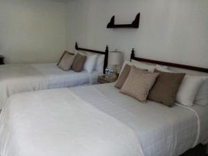 2 camas en una habitación de hotel con sábanas blancas en Hotel Posada Santa Fe, en Guadalajara