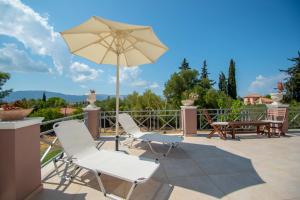 a patio with two chairs and an umbrella at Elegant Villa Zakynthos in Kalamaki