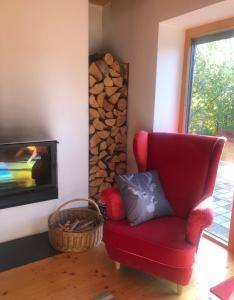 a red chair in a living room with a fireplace at Przystanek Klimczok in Szczyrk