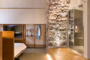 a bedroom with a bed and a stone wall at BASTIÒ PRIVATE SUITES in Catania