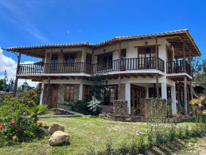 a large house with a porch and balcony at Hermoso lugar familiar cerca a Villa de Leyva in Sutamarchán
