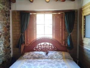 um quarto com uma cama de madeira e uma janela em Hermoso lugar familiar cerca a Villa de Leyva em Sutamarchán
