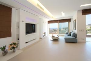 a living room with a tv and a blue couch at Villa Nelmar in Anavyssos