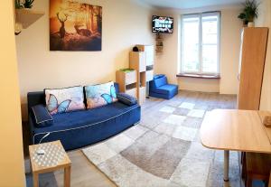 uma sala de estar com um sofá azul e uma televisão em Apartament "Na Halnej" centrum Krynicy, parking w cenie! em Krynica Zdrój