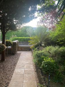 un jardín con un sendero de piedra y un banco en The Cottage, en Somerset West